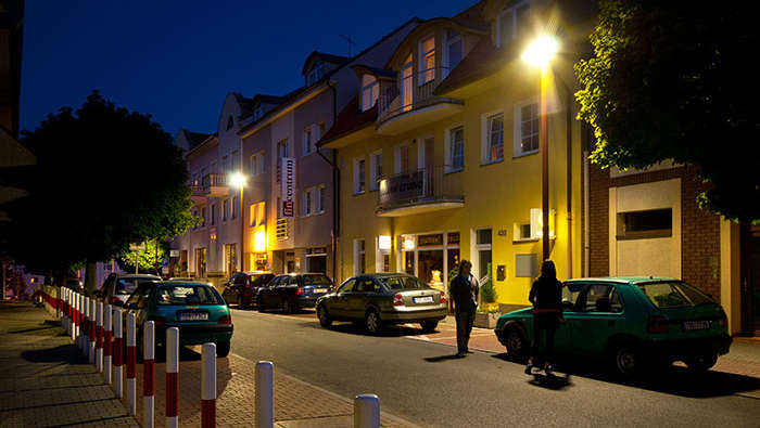 Piétons circulant la nuit dans une rue mise en lumière par une solution d'éclairage de la voie publique de Philips 