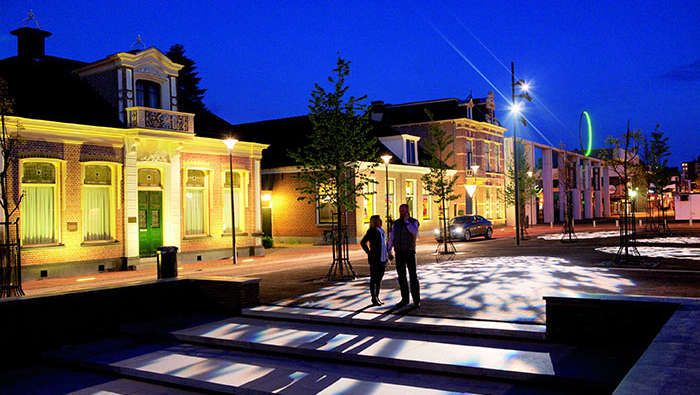 Een man en een vrouw wandelen op een plein dat is verlicht met licht van Philips