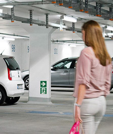Une femme se dirige vers sa voiture dans un parking souterrain non seulement bien éclairé mais qui s’inscrit dans une démarche durable avec la solution GreenParking