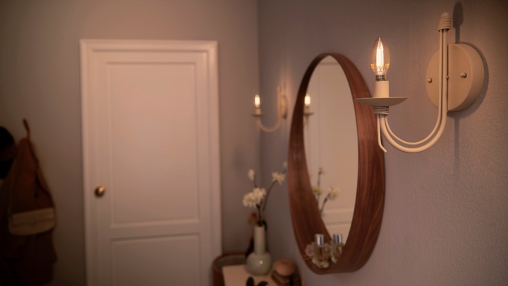 Kaarslampen aan weerszijden van een spiegel in de hal