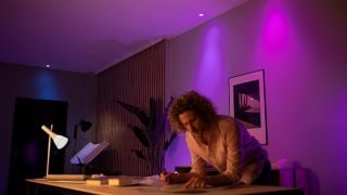 Philips Hue slimme LED-verlichting creëert een levendige paarse en roze sfeer in de woonkamer, met aanpasbare sfeerverlichting voor filmavonden en ontspanning in moderne huizen.