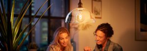"LED filament hanglamp in vintage stijl verlicht twee vrouwen die genieten van een avondgesprek en creëert een warme sfeer in een stedelijk appartement."