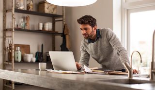 Man gebruikt laptop in goed verlichte thuiswerkplek met LED werkverlichting voor efficiënt werken op afstand.