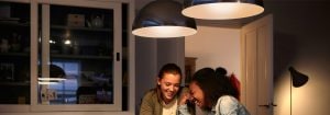"Moderne LED-hanglampen creëren een warme sfeer voor twee vrouwen die genieten van een gesprek en laten energiezuinige lichtoplossingen voor woningen zien."