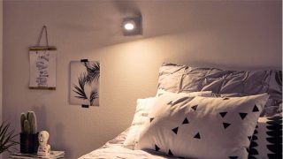 Stijlvolle slaapkamer met verstelbare LED spot die een gezellige sfeer creëert en geometrisch beddengoed en een minimalistische inrichting verlicht.